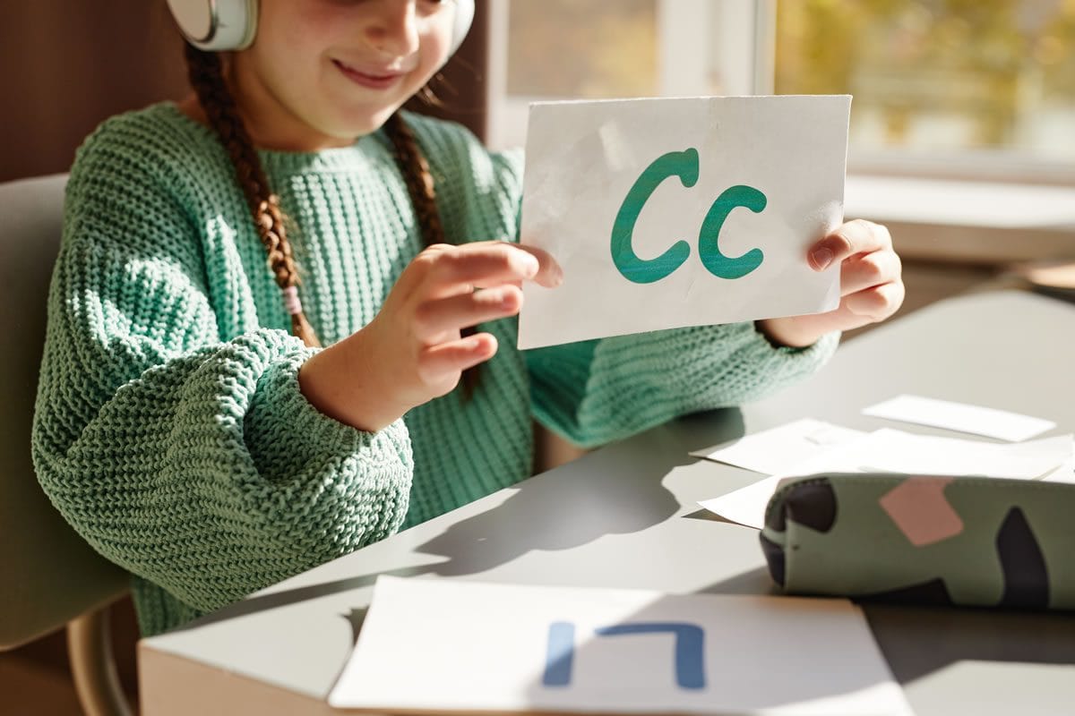 girl-practices-letters-with-flash-cards-at-table girl practices letters-with flash cards at table